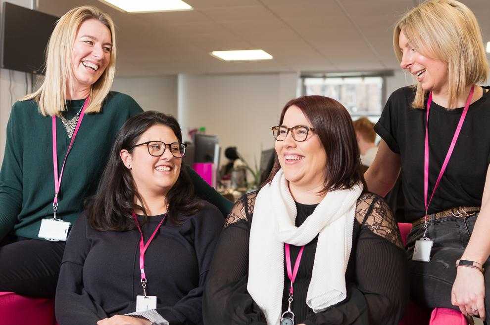 Four members of the Care Sourcer team smiling and laughing in the office